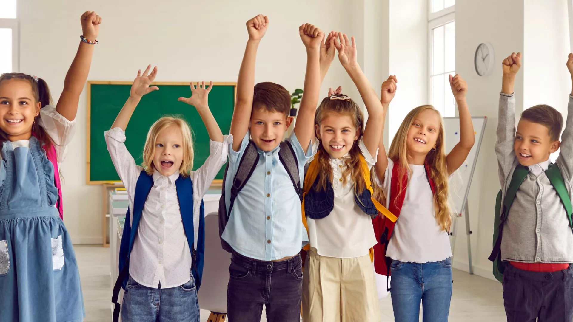 Enfant rieurs levant la main en salle de classe