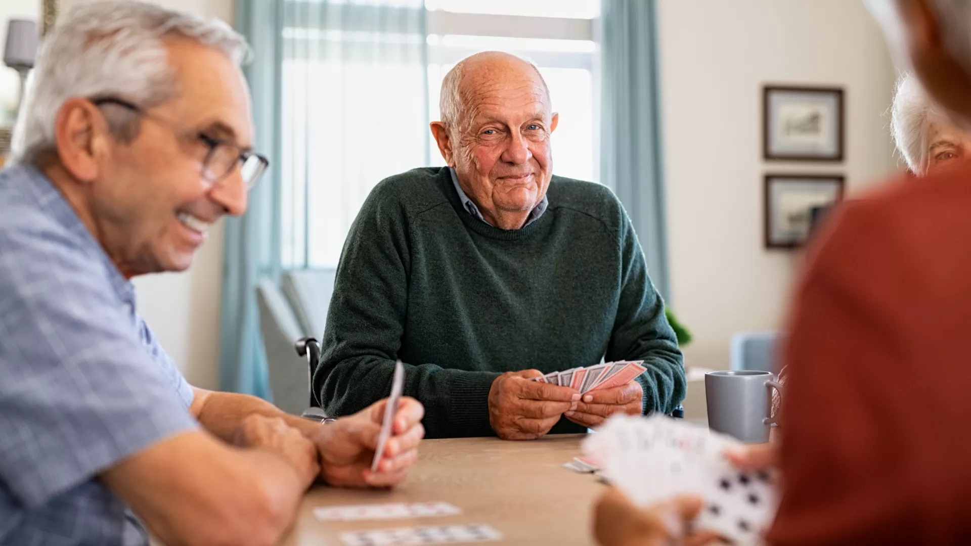 Homme âgé jouant aux cartes avec d'autres personnes