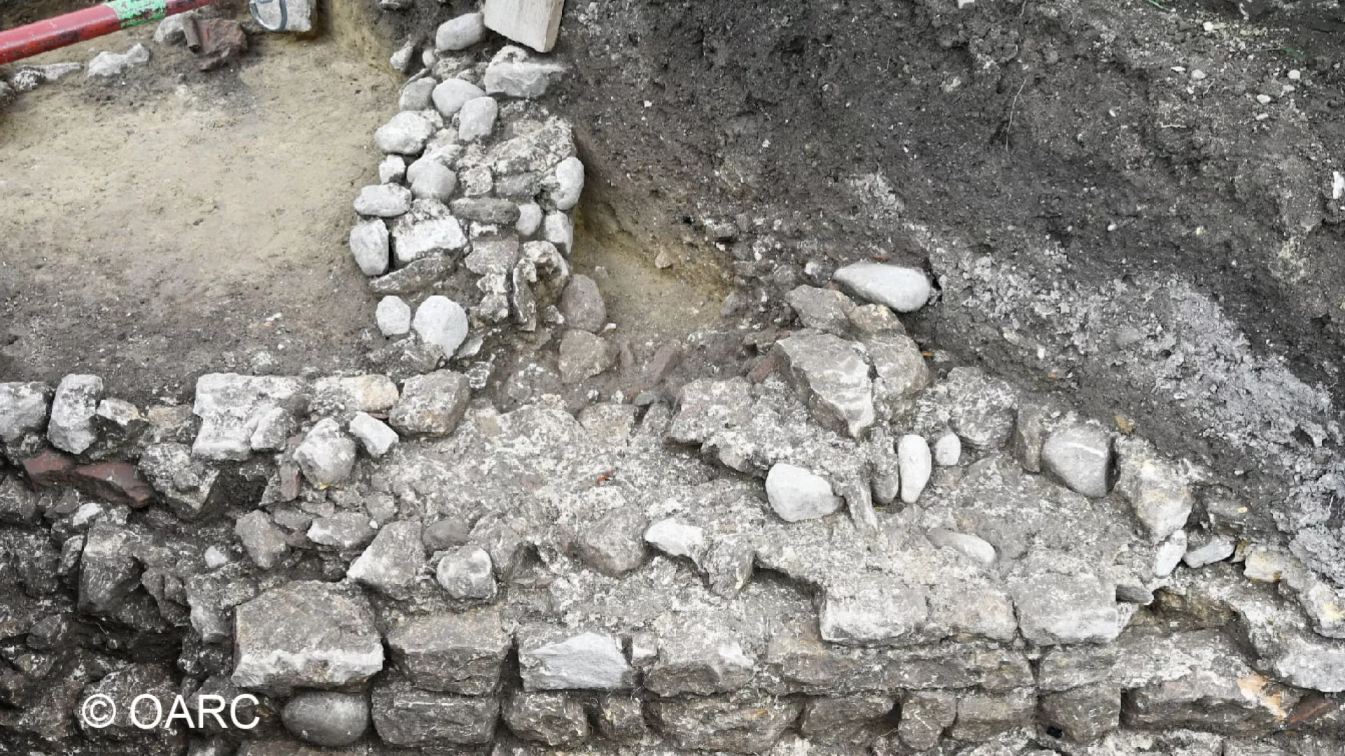 Deux murs et des sédiments foncés dans une tranchée étroite
