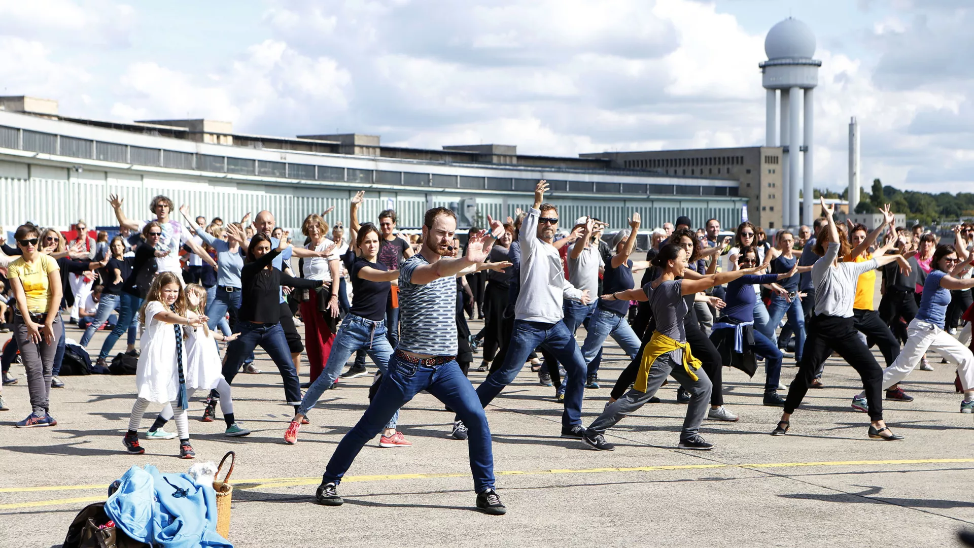 Une foule danse sur le tarmac d'un aéroport.