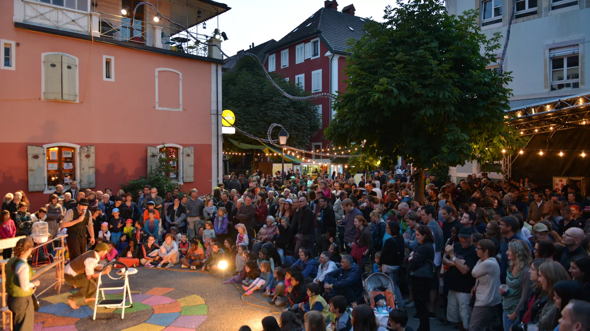 Un public nombreux assiste à un spectacle d'arts de la rue à La Chaux-de-Fond à la fin du jour.