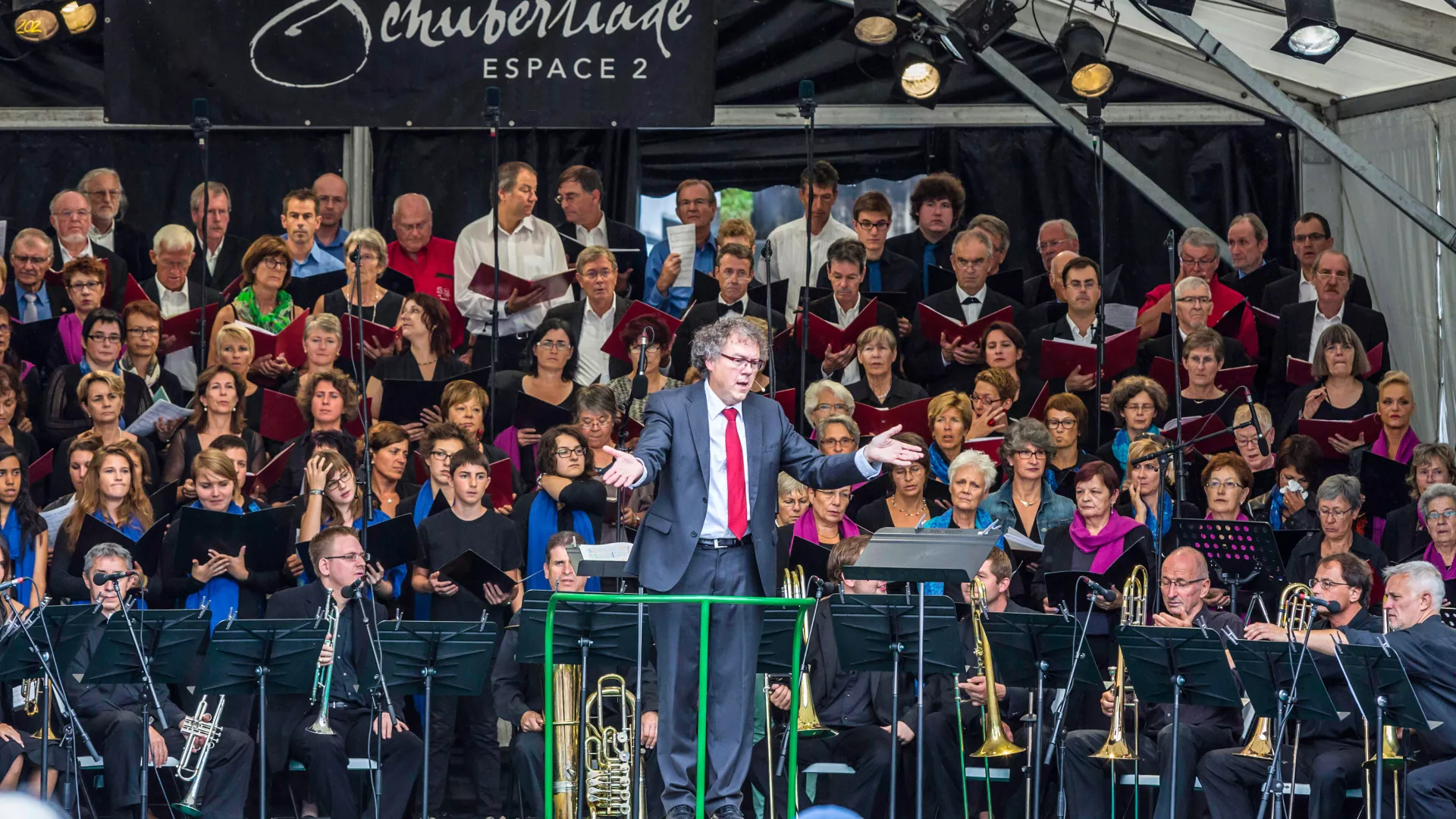 Un ensemble musical et son chef devant un public.