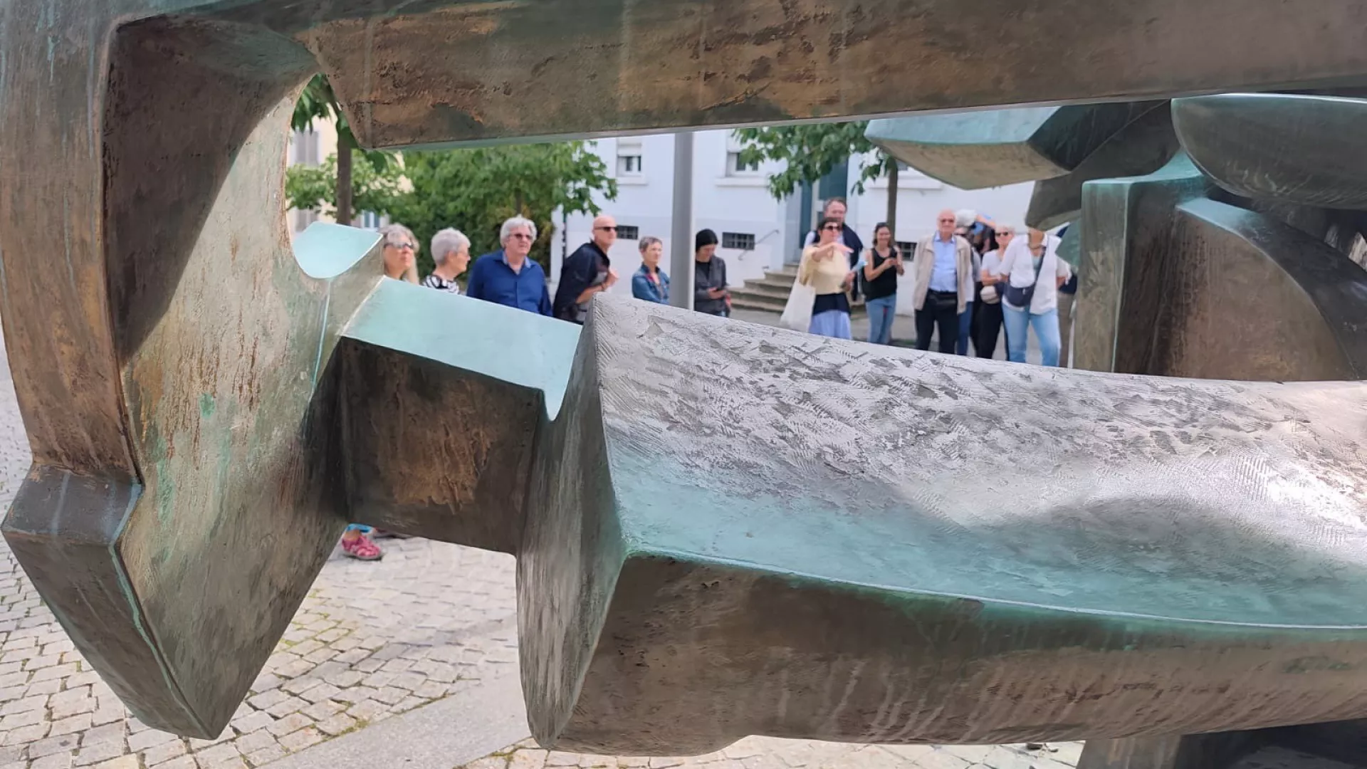 Vue d'un groupe de visiteurs à travers une sculpture en bronze