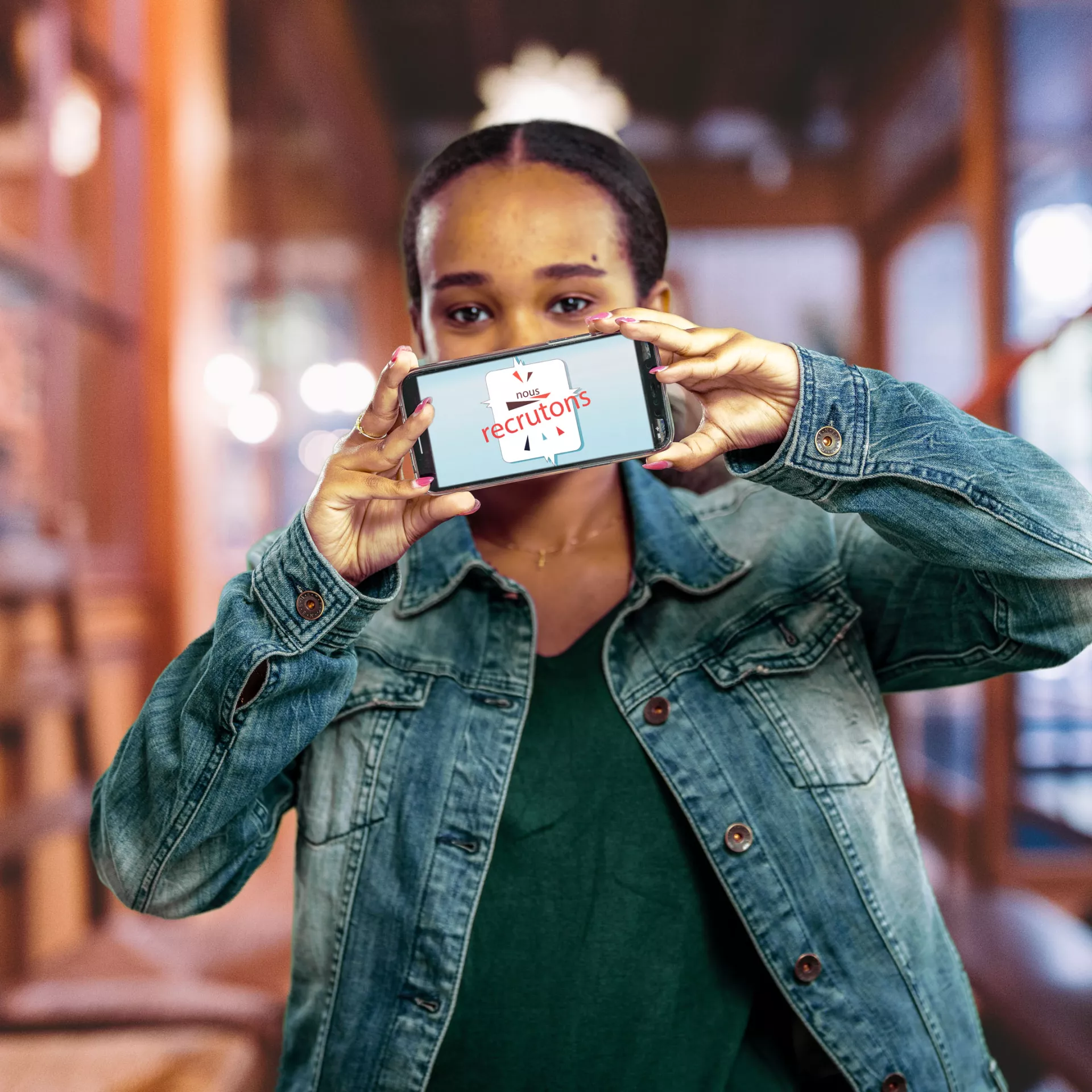 Personne qui tient un téléphone sur lequel figure "Nous recrutons"